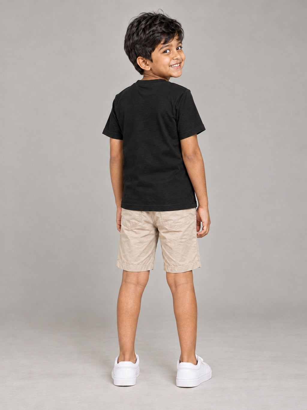 Little Kaavo kids crew tee in black, plain back, worn by a young boy, back view