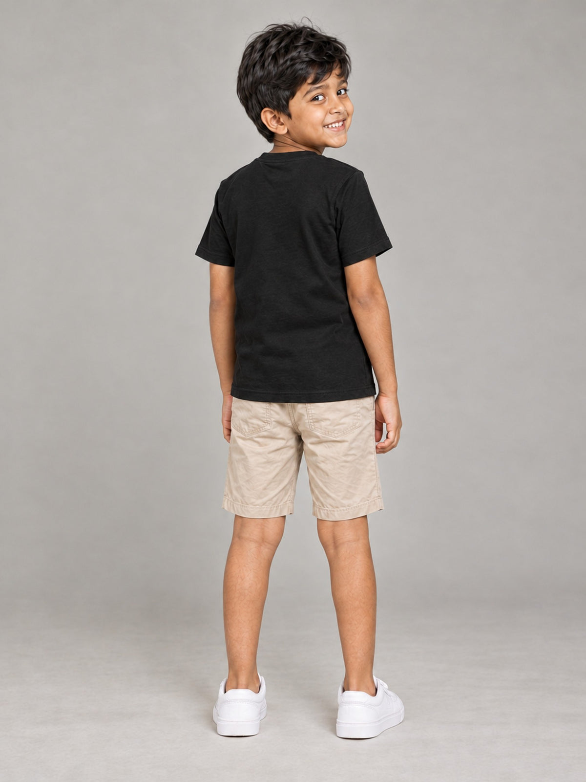 Little Kaavo kids crew tee in black, plain back, worn by a young boy, back view